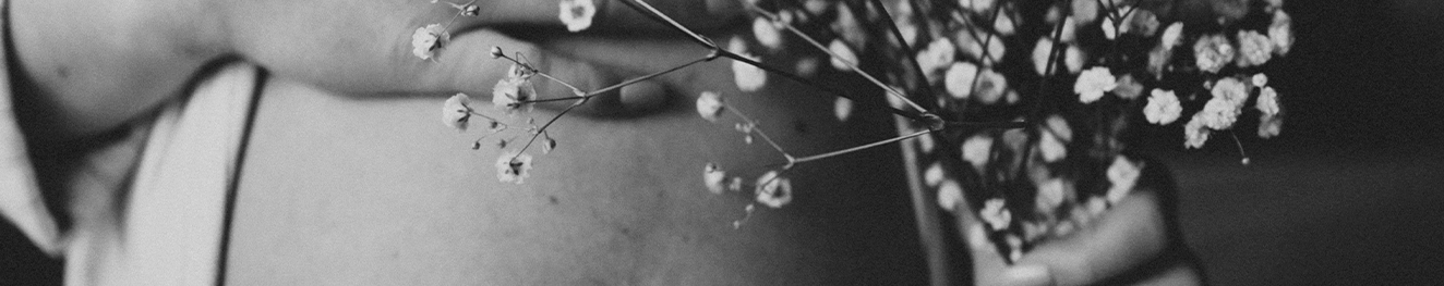 Foto en blanco y negro de mujer embarazada con ramo de flores silvestres en la mano