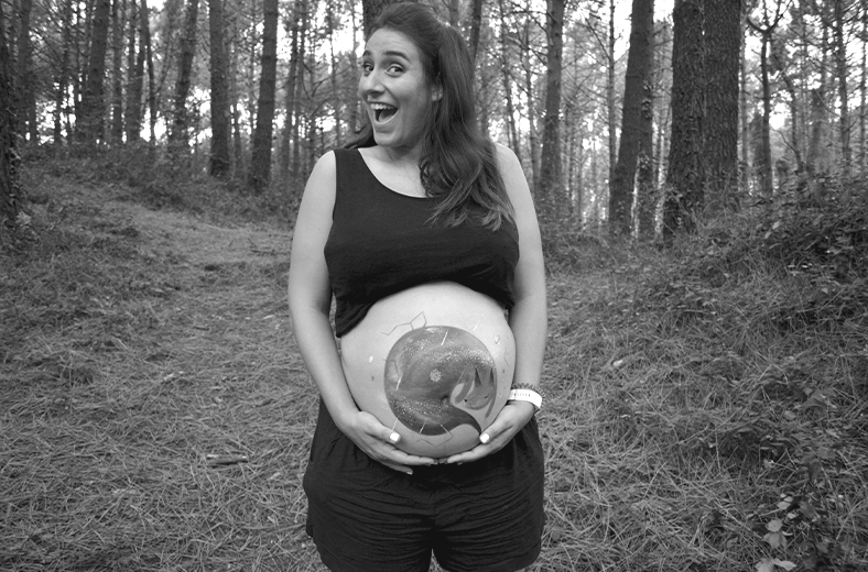 Foto en blanco y negro de mujer embarazada mostrando body paint hecho en su barriga